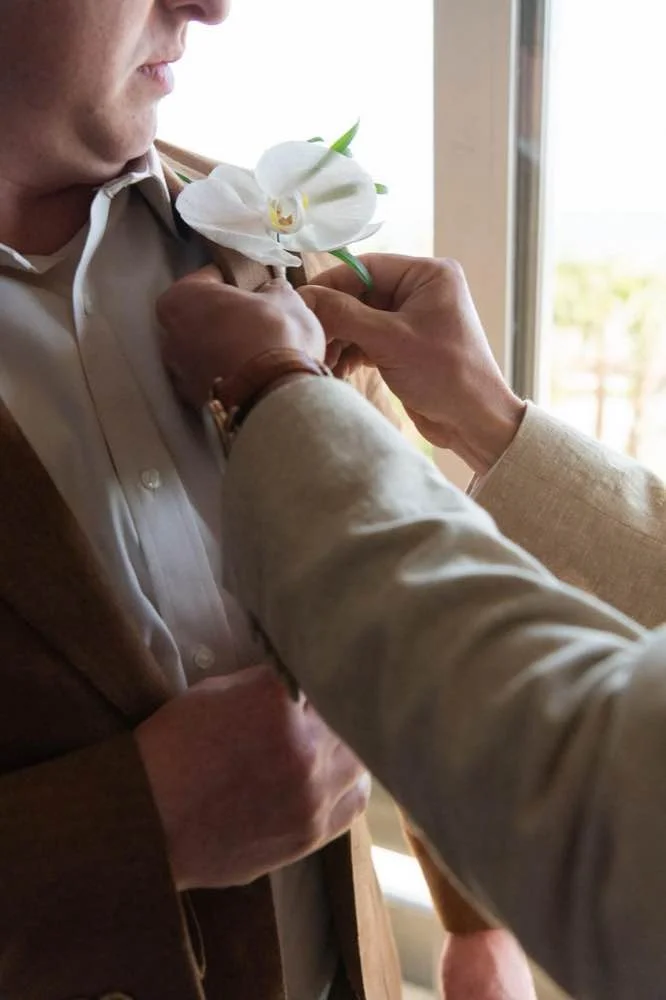 Close up of groom being pinned by his best man